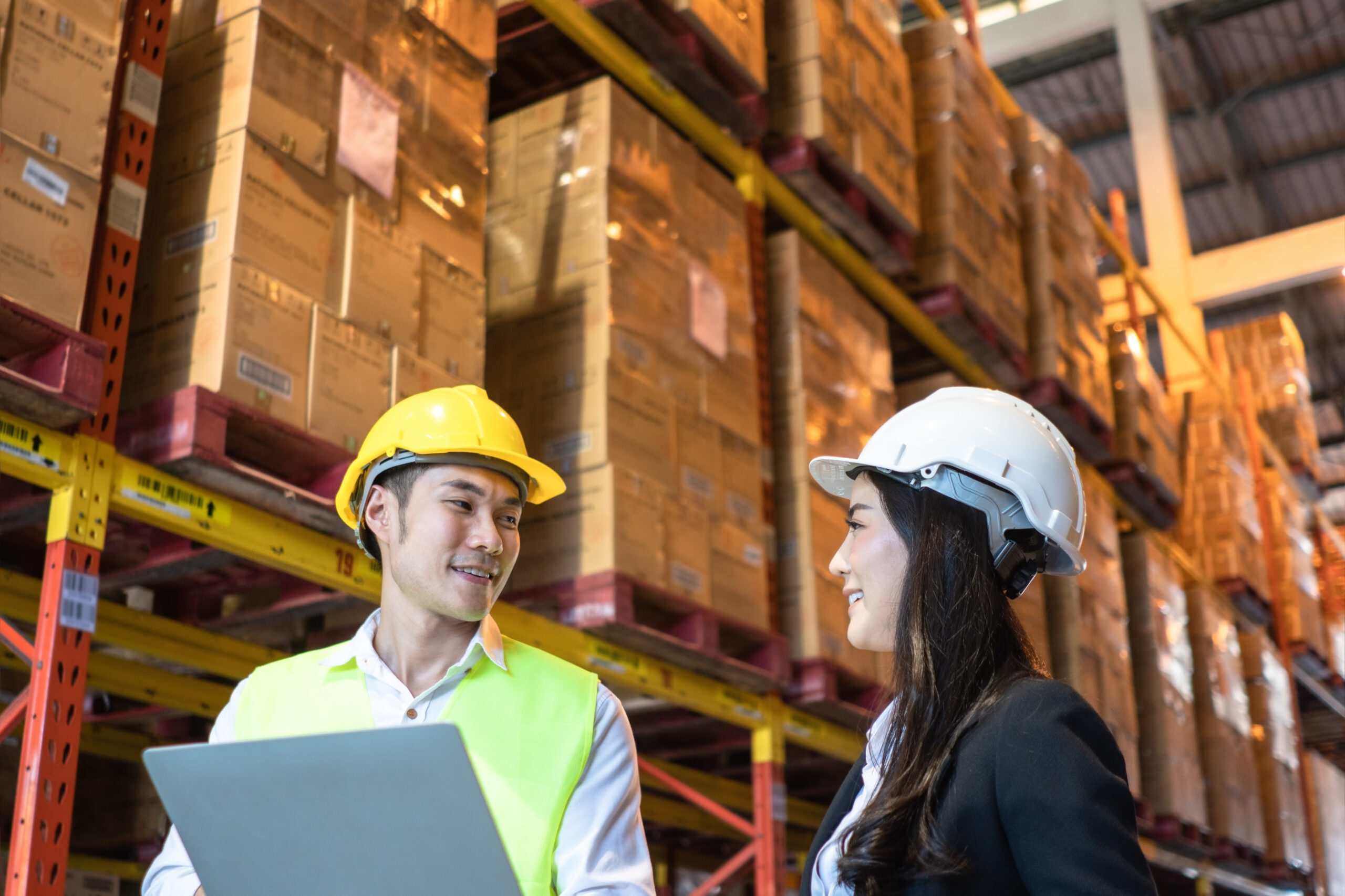 A male and female employee are having a conversation in a warehouse.