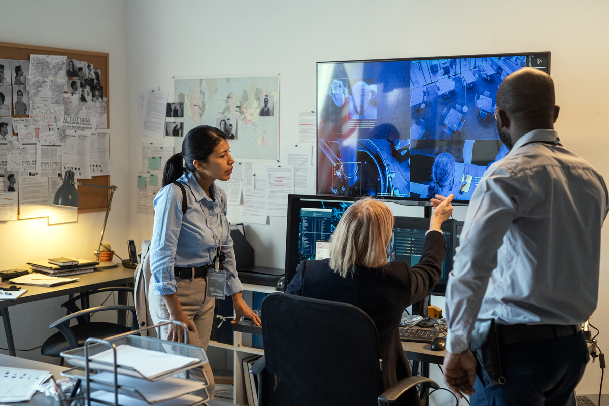 Three people in an office watching security camera footage