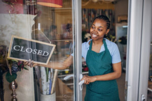 Small business owner placing a "closed" sign in the window of her shop to notify customers that her business will not be open during the holidays.