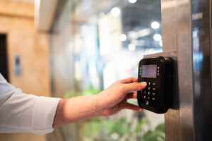 Office employee entering in a passcode to a keypad operated electronic door lock.