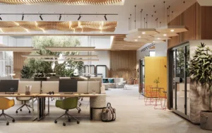 The interior of a modern office space. This set up is an open concept, with warm colors, plants, and artistic lighting for a more inviting work environment. Offices such as these are often partt of the start-up space.